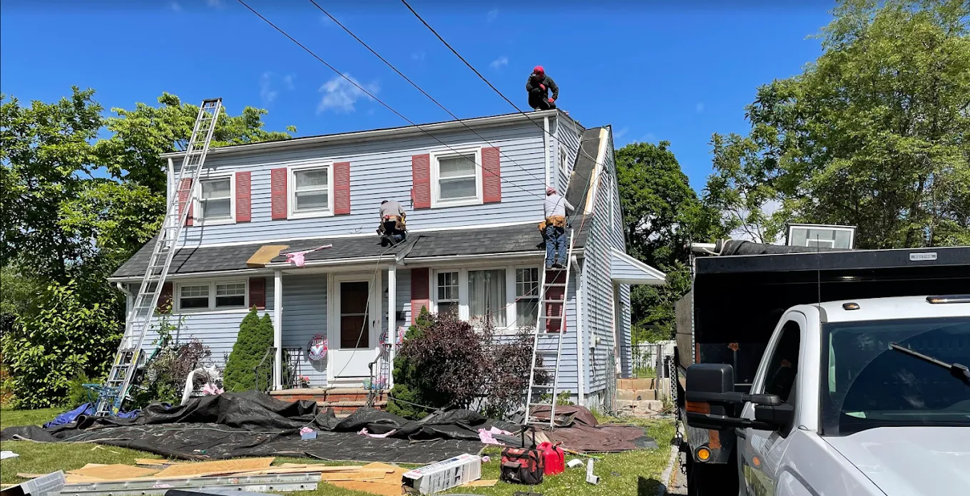 AAA Apex roofers on ladders and the roof of a light blue two-story house