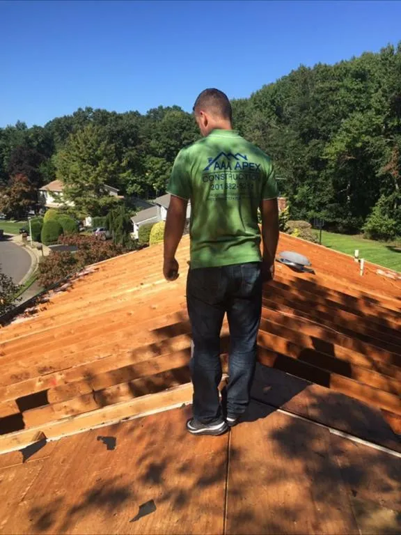 A roofer in an AAA Apex shirt standing on newly laid roof decking