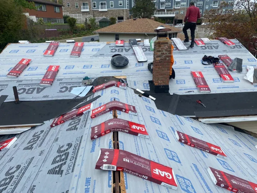 Synthetic underlayment covering a roof with GAF shingle bundles and a brick chimney