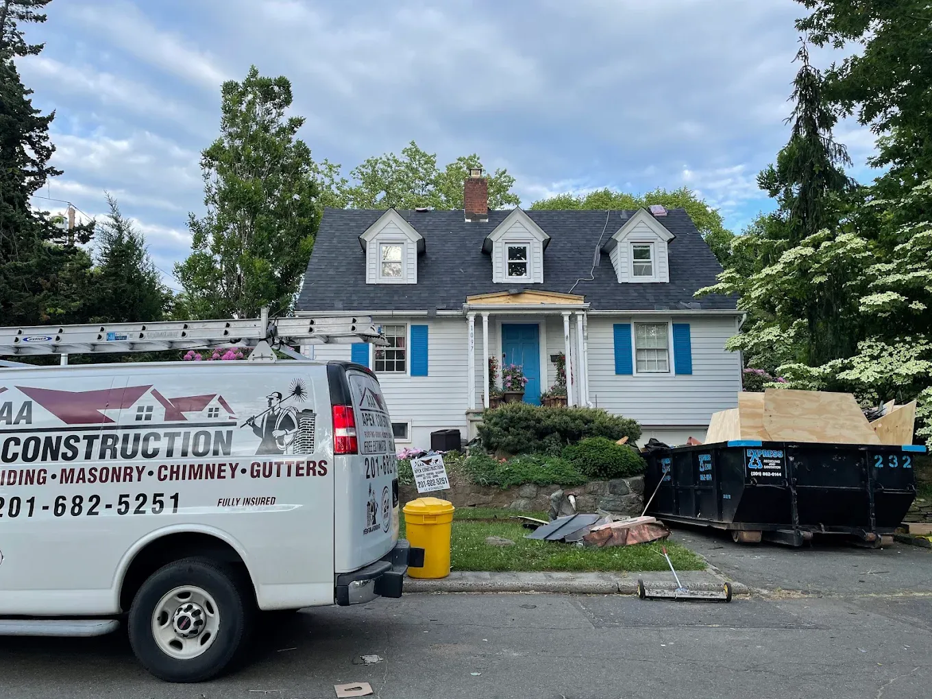 The AAA Apex van in front of a white Cape Cod house with blue shutters and three dormers